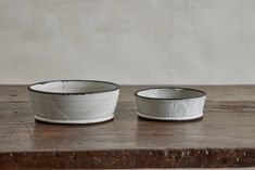 two white bowls sitting on top of a wooden table