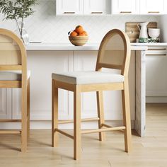 two stools in a kitchen next to a bowl of fruit on the counter top