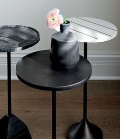 two black tables with flowers on them and one has a white flower in the vase