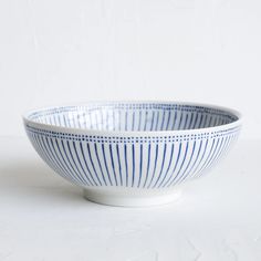 a blue and white striped bowl sitting on top of a white tableclothed surface