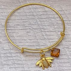 This Listing s for this Pretty Antique Gold Bee with a dainty Topaz Swarovski Crystal  on gold plated bangle Bracelet. This bracket was make with a cute double sided Antique Gold bee charm on heavy duty gold plated jump ring and a Sparkle Topaz Swarovski Crystal  (11.5mm) Princess cut pendant.  What a beautiful  bracelet to give her on her birthday.  Your bracelet will come in a gift box ready to give as a gift. PLEASE READ BEFORE PLACING YOUR ORDER: FREE SHIPPING FOR ORDERS OVER $35.00 Offer ON Adjustable Gold-tone Charm Bracelet Gift, Adjustable Yellow Gold Dangle Charm Bracelet, Nickel-free Gold Bangle Charm Bracelet, Adjustable Gold-plated Bracelet With Charms, Adjustable Gold-plated Charm Bracelet, Gold Nickel-free Bangle Charm Bracelet, Adjustable Gold Plated Bracelet With Charms, Yellow Gold-plated Bangle For Gift, Yellow Gold-plated Bangle As Gift