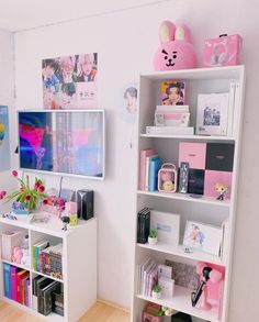 a white book shelf filled with books next to a wall mounted flat screen tv on top of a wooden floor