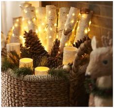 a basket filled with candles sitting next to a stuffed animal and christmas trees in front of a fire place