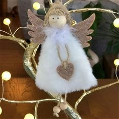 a white angel ornament sitting on top of a wooden table next to christmas lights