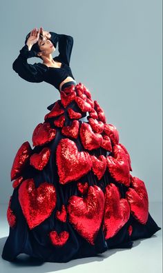 a woman in a red and black dress with hearts on the skirt is posing for a photo