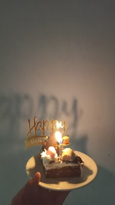 a person holding a plate with a piece of cake on it that says happy birthday