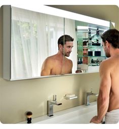 a man standing in front of a bathroom mirror looking at his reflection in the mirror