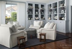 a living room filled with white furniture and lots of bookshelves on the wall