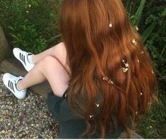 a woman with long red hair is sitting on a bench and has her back to the camera