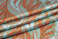 an orange and blue fabric with large leaves on the top, in front of a white background