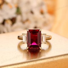 a close up of a ring with a red and white stone in it on a table