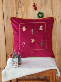 a red pillow sitting on top of a wooden chair next to a small christmas tree