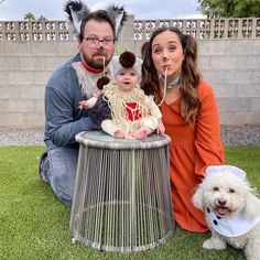 a man and woman pose for a photo with two small dogs in front of them