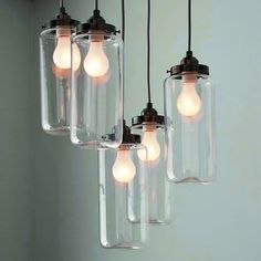 four glass jars with light bulbs hanging from the ceiling in a kitchen or dining room