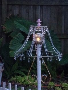 a lamp that is sitting on top of a pole in the grass next to a fence