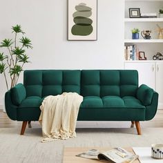 a living room with a green couch and potted plant on the floor next to it