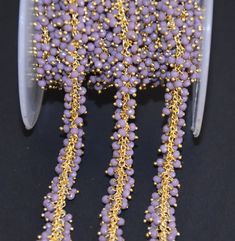 purple and gold beaded chain on a black surface with white plastic spools