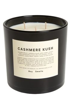 a black candle that is sitting on a white surface with the words cashmere kush printed on it