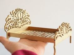 a hand holding a miniature bed made out of wood