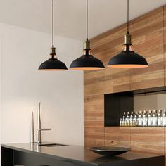 three pendant lights hanging from the ceiling above a bar