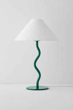 a green table lamp sitting on top of a white floor next to a light bulb