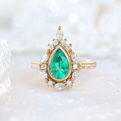 an emerald and diamond ring on a white surface