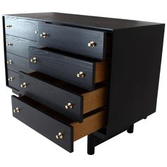 a black dresser with three drawers and gold knobs on the bottom drawer, against a white background