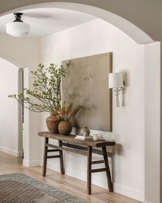 a vase with some flowers sitting on top of a table next to an archway in a room