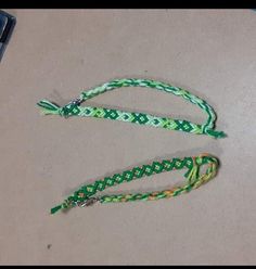 two green and white braided lanyards sitting on top of a table next to a cell phone