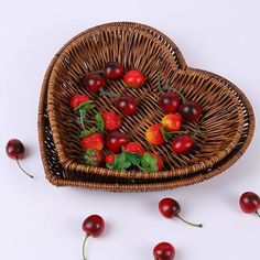 a heart shaped basket filled with cherries and strawberries