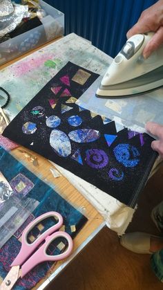 a person ironing fabric on top of a table next to scissors and other craft supplies