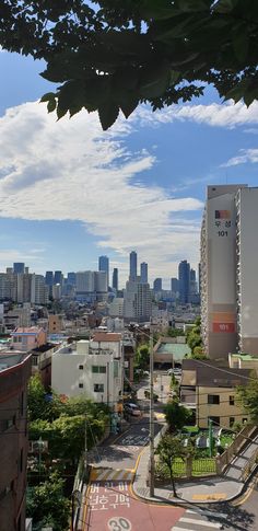 a city with tall buildings and lots of trees in the foreground, on a sunny day