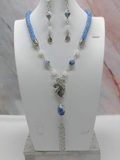 "Handmade and designed by me-one of a kind necklace set-blue seed bead crocheted rope necklace-22\" long-2 1/2\" long chain tassel with a sodalite nugget-sodalite accent beads-matte frosted dragon vein agate cube beads-metsl beads-3 1/4\" long dangle earrings with a flower charm-antique silver tone leaf toggle clasp in front-antique silver tone findings. Make this unique necklace set a great addition to your jewelry collection! Would make a statement when adding to your summer outfit!" Blue Macrame Jewelry With Round Beads, Crochet Gemstone, Necklace Matching, Bead Crochet Rope, Dragon Vein Agate, Crochet Rope, Earrings Pendant, Long Dangle Earrings, Craft Set