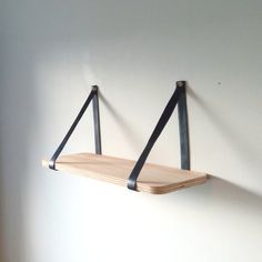 two wooden shelves with metal straps hanging on the wall