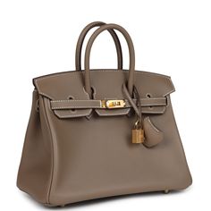 This Birkin is in Etoupe swift leather with gold hardware and has contrast stitching, front flap, two straps with center toggle closure, clochette with lock and two keys, and double rolled handles.The interior is lined with Etoupe chevre and has one zip pocket with an Hermes engraved zipper pull and an open pocket on the opposite side.Collection: BOrigin: FranceCondition: New and never worn (plastic on hardware) Accompanied by: Hermes box, Hermes dustbag, felt, clochette, lock, 2 keys, clochette dustbag, carebook, ribbonMeasurements: 10" width x 7.5" height x 4.75" depth; 2.75" handle drop Birkin 25 Etoupe, Hermes Purse, Hermes Birkin 25, Hermes Box, Birkin 25, Madison Avenue, Hermes Birkin, Gold Hardware, Zip Pockets