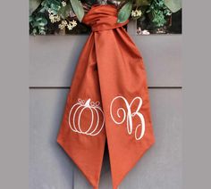 the monogrammed pumpkins are tied to the front of this door hanger