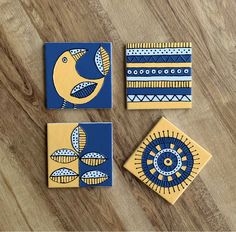 three blue and yellow ceramic coasters with designs on them sitting on a wooden surface