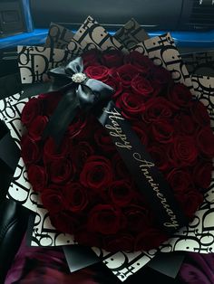 a heart shaped box filled with red roses on top of a purple and black blanket