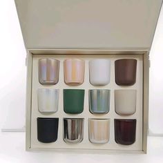 a box filled with lots of different colored glass cups on top of a white table