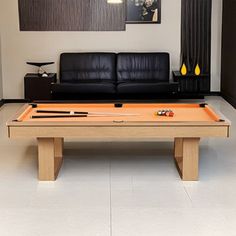 a pool table in the middle of a room with couches and pictures on the wall