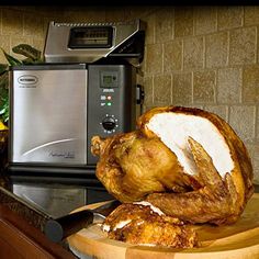 a whole chicken sitting on top of a cutting board next to a toaster oven