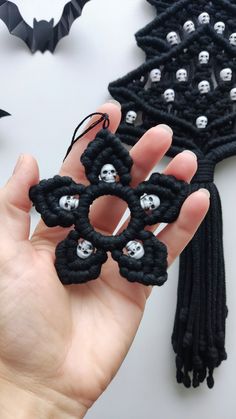 a hand holding a black and white beaded brooch with skulls in the middle