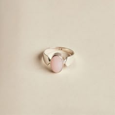 The Pink Opal is a lovely stone to wear. Its soft, baby pink oval cabochon is highlighted by the band's design. The ring is made with 925 sterling silver. The ring is available in size 7 1/4. Dimensions: Total height: 13mm Total width: 8mm Stone height: 12mm Stone width: 8mm Stone + bezel thickness: 6mm Band width: 7mm to 3mm - Please note - * Additional photos and videos available on request * Go to 'About us' section for links to our socials and website * Only the ring from first picture is in Adjustable Oval Cabochon Moonstone Ring, Large Oval Moonstone Ring, Elegant Oval Pink Opal Ring, Classic Handmade Oval Moonstone Ring, Pink Oval Opal Ring In Sterling Silver, Oval Pink Opal Ring Gift, Oval Pink Opal Gemstone Rings, Adjustable Oval Opal Ring Minimalist Style, Oval Pink Opal Ring For Gift