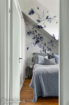 a bed sitting under a stair case next to a wall with blue flowers on it