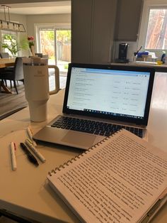 an open laptop computer sitting on top of a table next to a notebook and pen