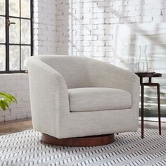 a white chair sitting on top of a rug in front of a window next to a potted plant