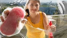 a woman holding up a pink object in front of her face with water splashing all over it