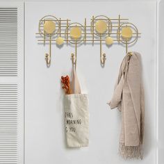 a coat rack with two coats hanging from it's hooks next to a bag