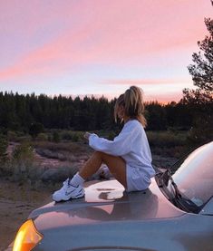 a woman sitting on the hood of a car