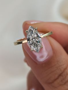 a close up of a person holding a ring with a large diamond in the middle